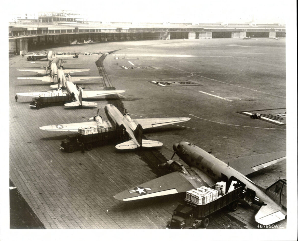 Řada transportních letadel C-47 a vykládací týmy na letišti Tempelhof