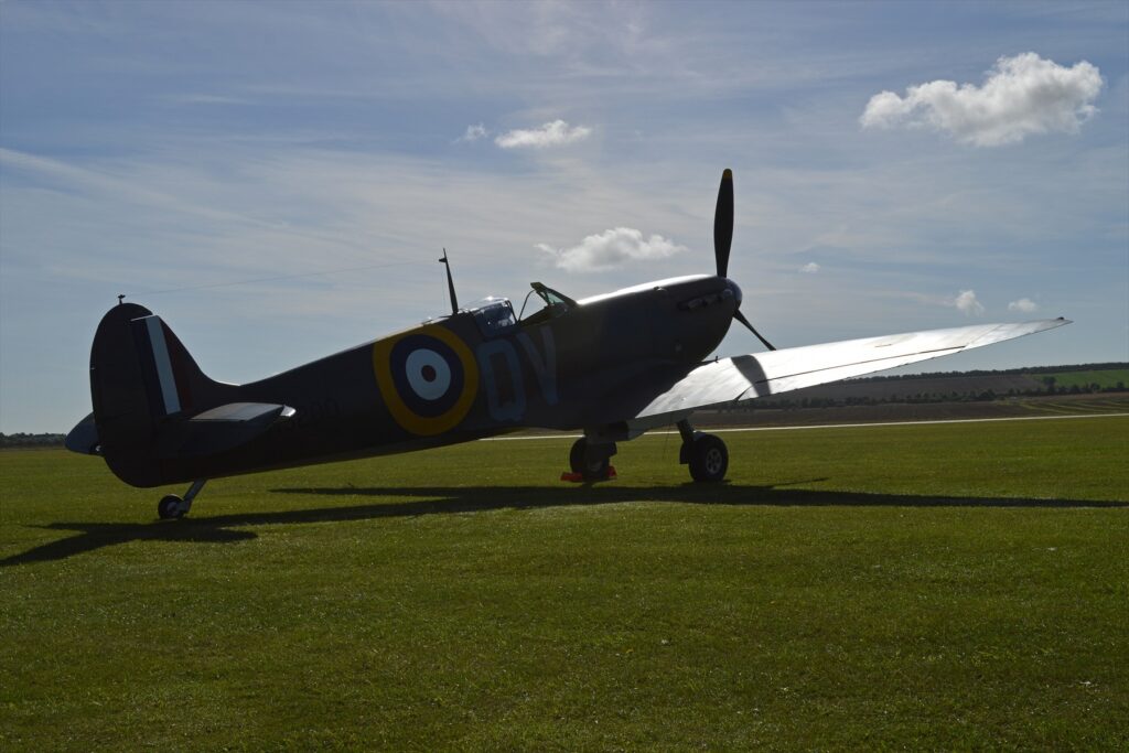 Britská stíhačka Supermarine Spitfire s točící se vrtulí připravená ke startu na letištní ploše.