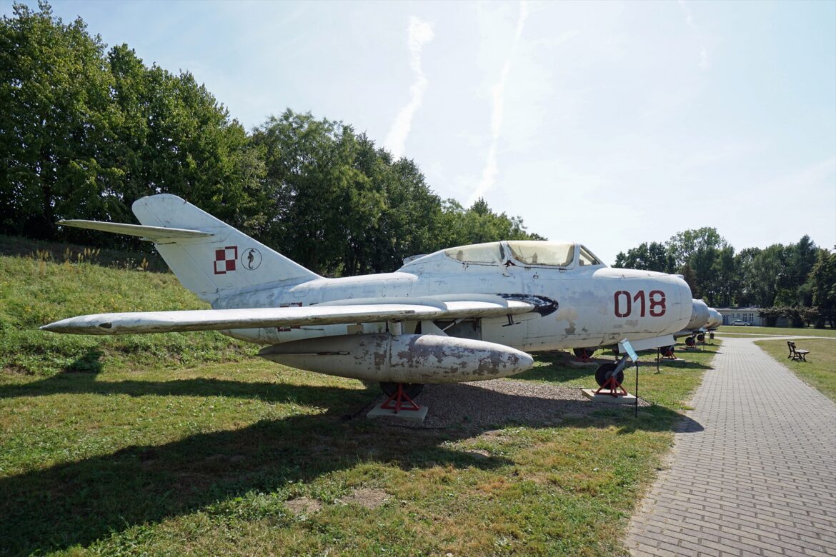 Stříbrný proudový stíhací letoun MiG-15 vystavený na travnaté ploše muzea