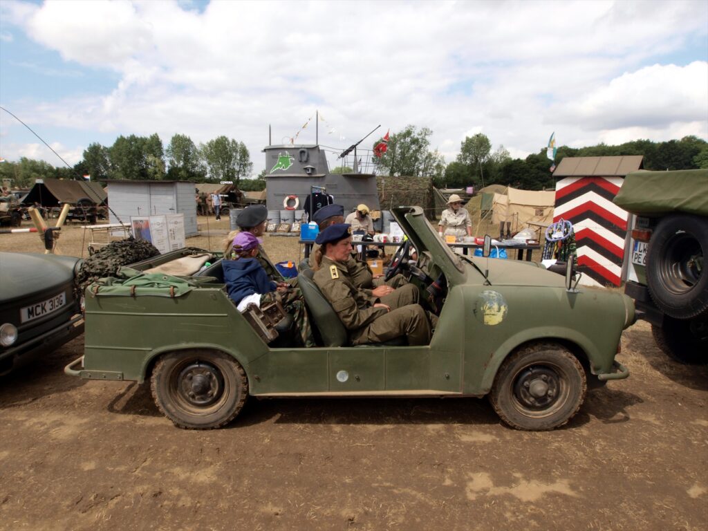 Zelený otevřený Trabant Kübel se dvěma lidmi na přehlídce, pohled z boku.