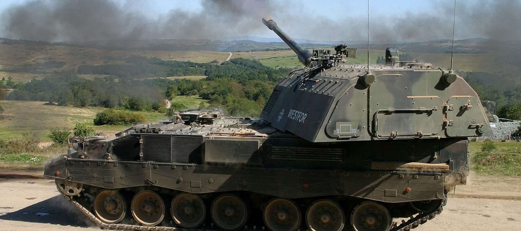 Německá samohybná houfnice Panzerhaubitze 2000 v palebném postavení při ostrém výstřelu s plamenem na ústí hlavně