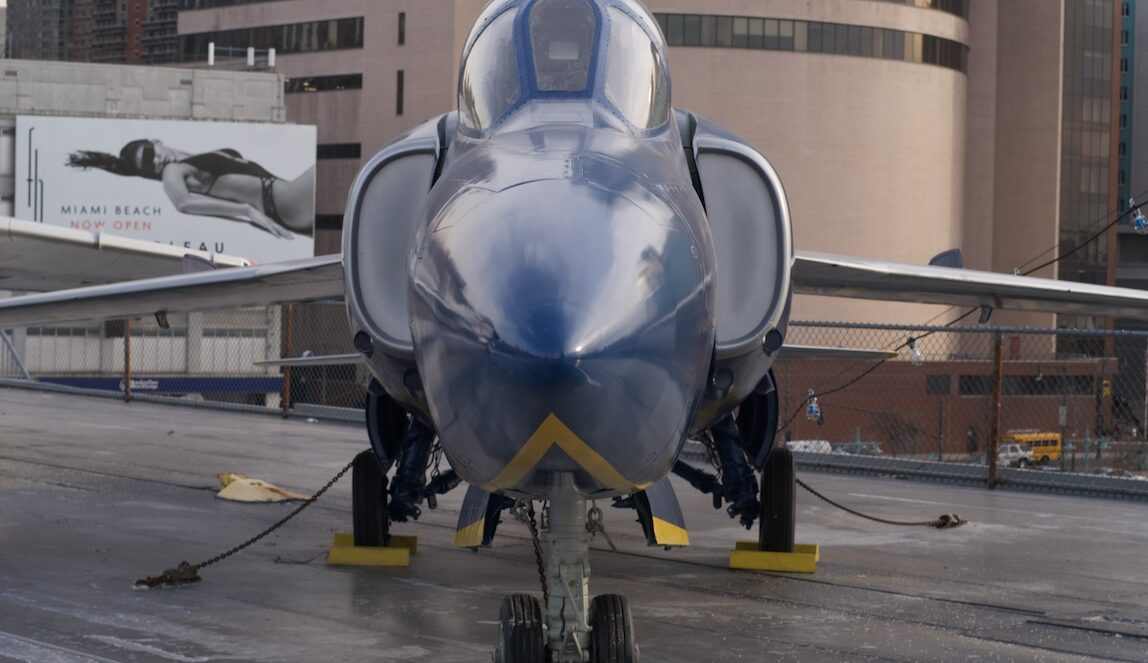 Jednomístný proudový letoun Grumman Tiger v šedo-bílém nátěru amerického námořnictva na letištní ploše