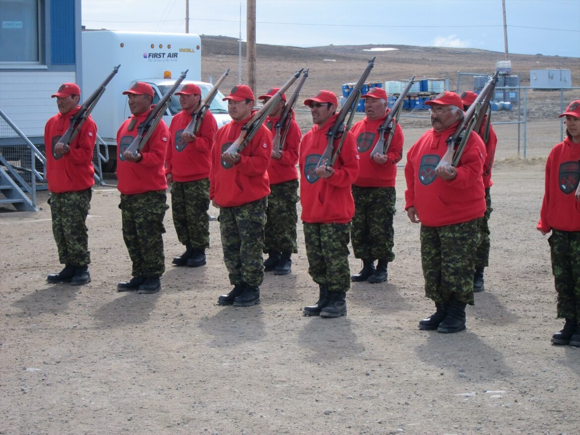 Kanadští Rangers v červených mikinách stojí v řadě s puškami Lee-Enfield.