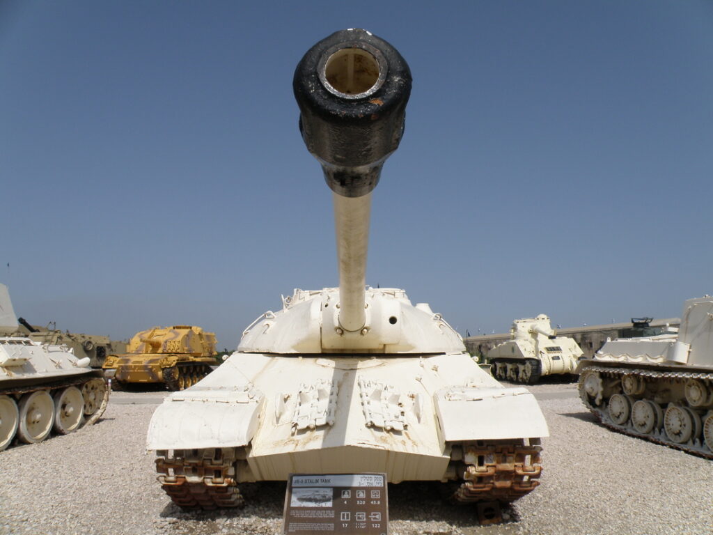 Čelní pohled na světlý tank IS-3 s nízkou zaoblenou věží a dělem namířeným k fotoaparátu.