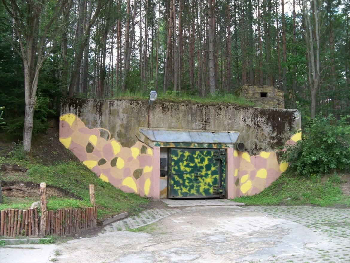Těžká pancéřová tlaková vrata a betonový vjezd do podzemního vojenského bunkru.