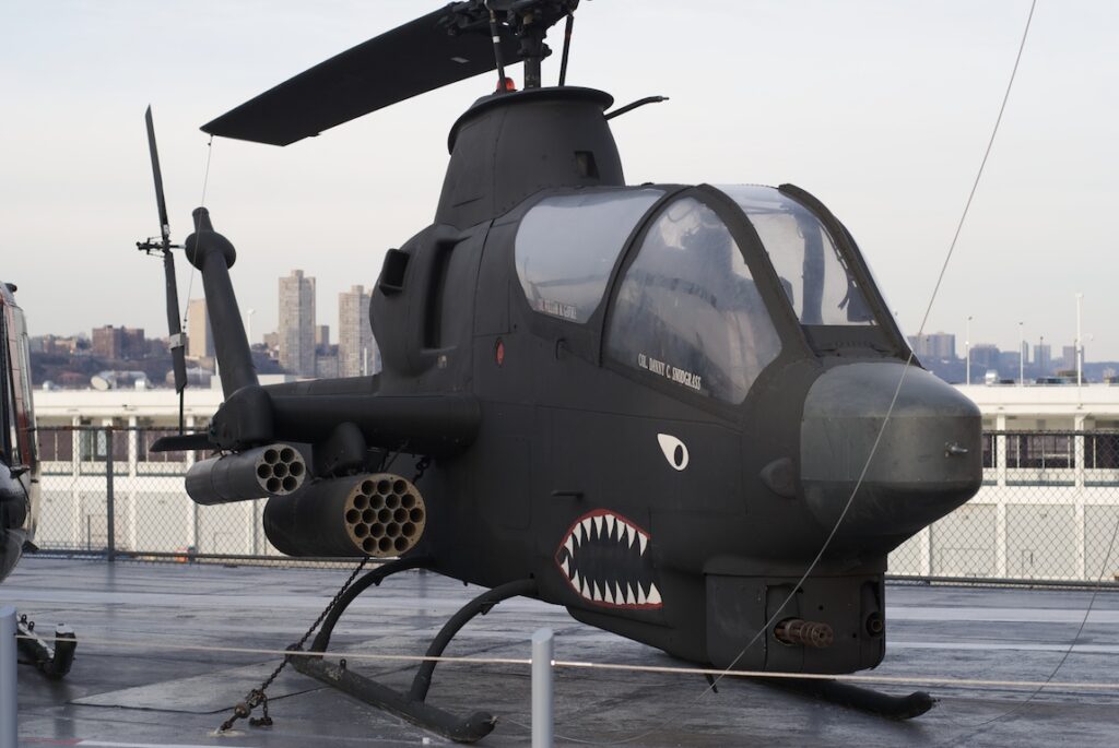 Jednomotorový bitevní vrtulník Bell AH-1 Cobra s podvěšenou výzbrojí a úzkým profilem trupu.