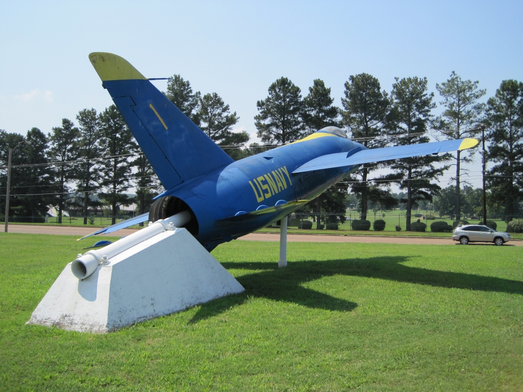 Historický stíhací letoun F11F-1 Tiger v tmavě modrém zbarvení s žlutými nápisy umístěný na památníku