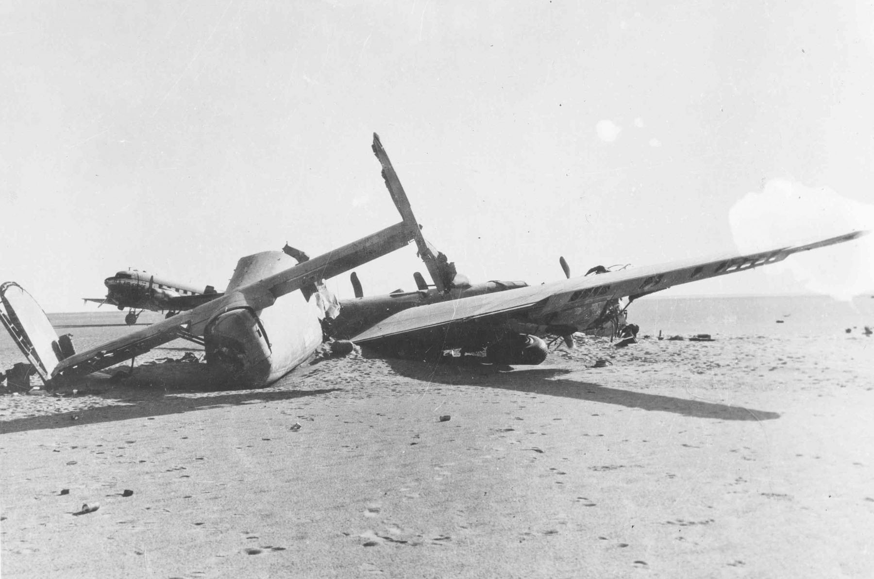 Pohled na zadní střeliště a dvojitou směrovku bombardéru Lady Be Good s pátracím letounem C-47 v pozadí