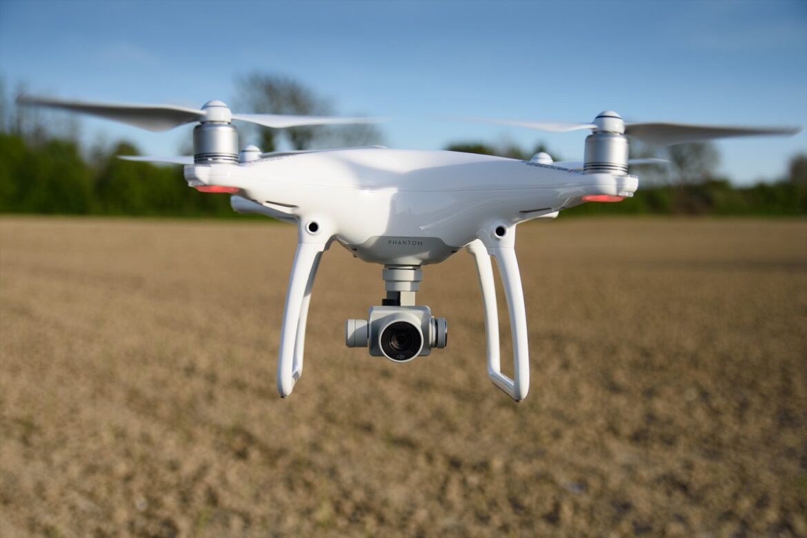 Bílá kvadrokoptéra DJI Phantom 4 v letu.