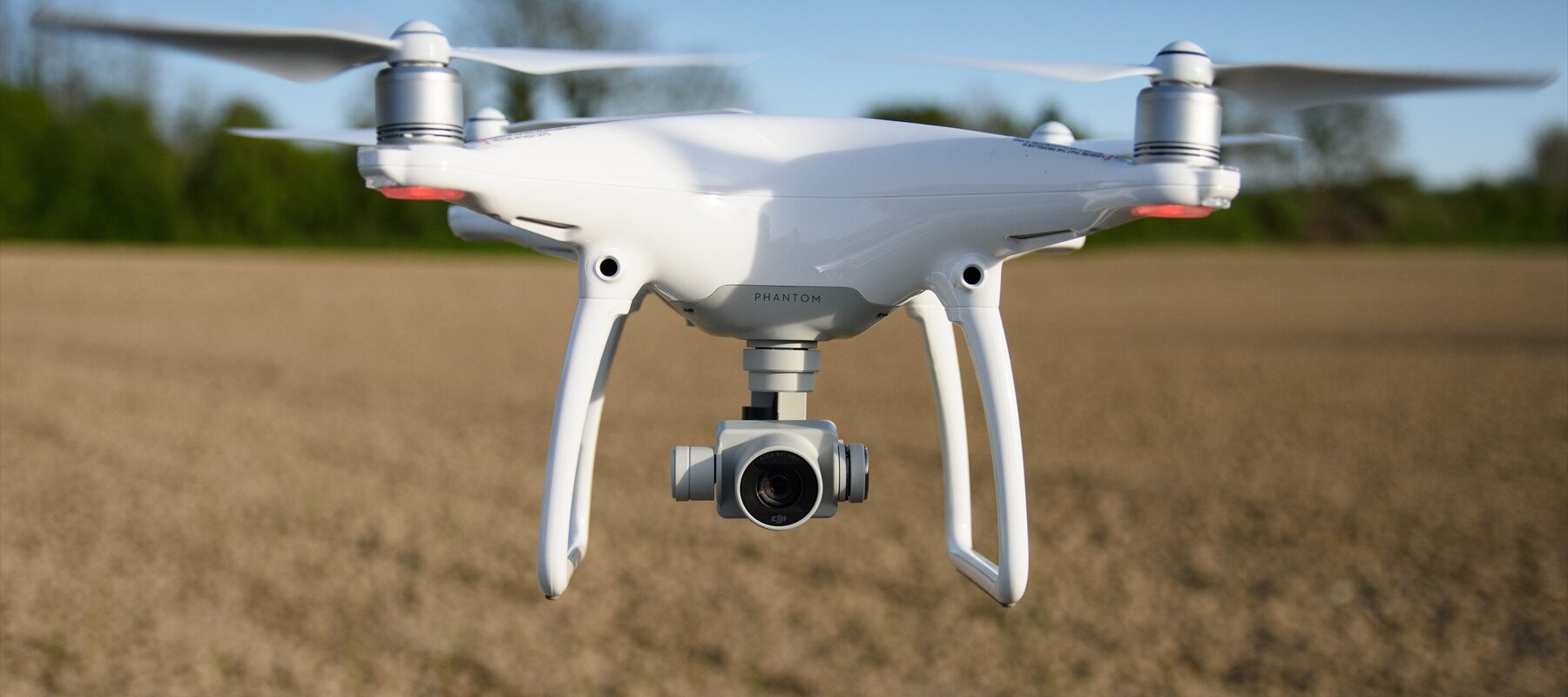 Bílá kvadrokoptéra DJI Phantom 4 v letu.