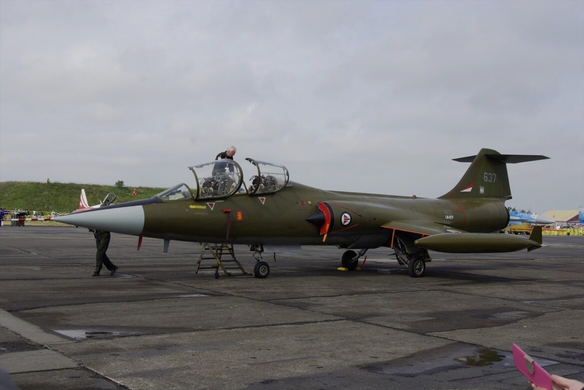 Zelený dvoumístný Starfighter LN-STF s číslem 637 a otevřenými kabinami na letištní ploše.