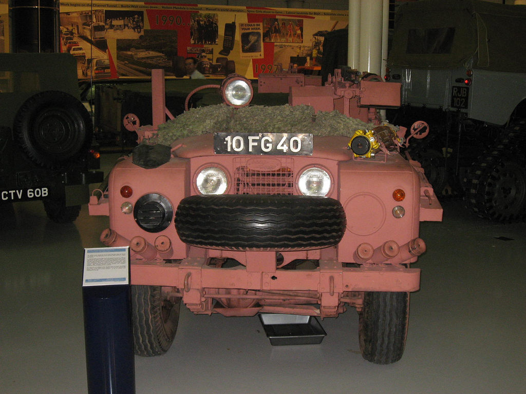 Čelní pohled na růžový Land Rover s registračním označením 10 FG 40 a rezervním kolem.
