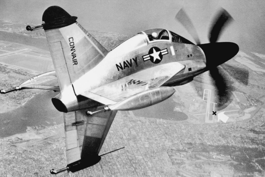 Stříbrný Convair XFY-1 Pogo s roztočenými vrtulemi při letu nad krajinou