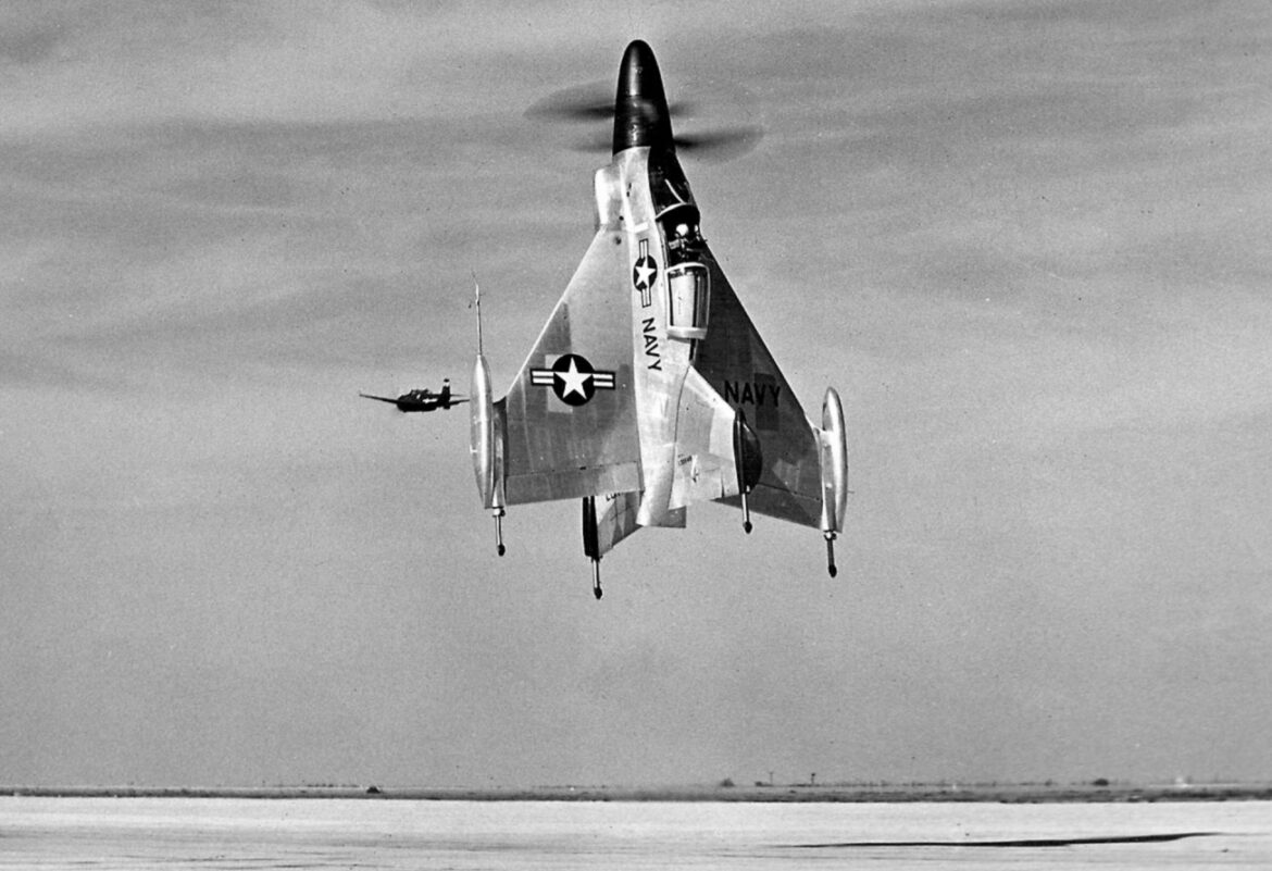 Convair XFY-1 Pogo s přídí vzhůru nad letištěm, v pozadí další letoun