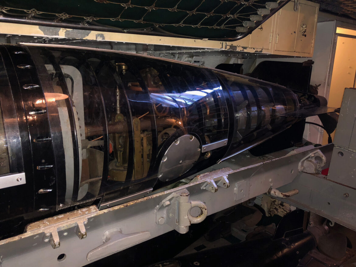 Vnitřní mechanismy elektrického torpéda za průhledným krytem na muzejní ponorce USS Pampanito.
