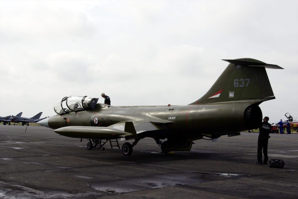 Starfighter LN-STF z levé zadní strany, s otevřenými kabinami a lidmi u letounu.