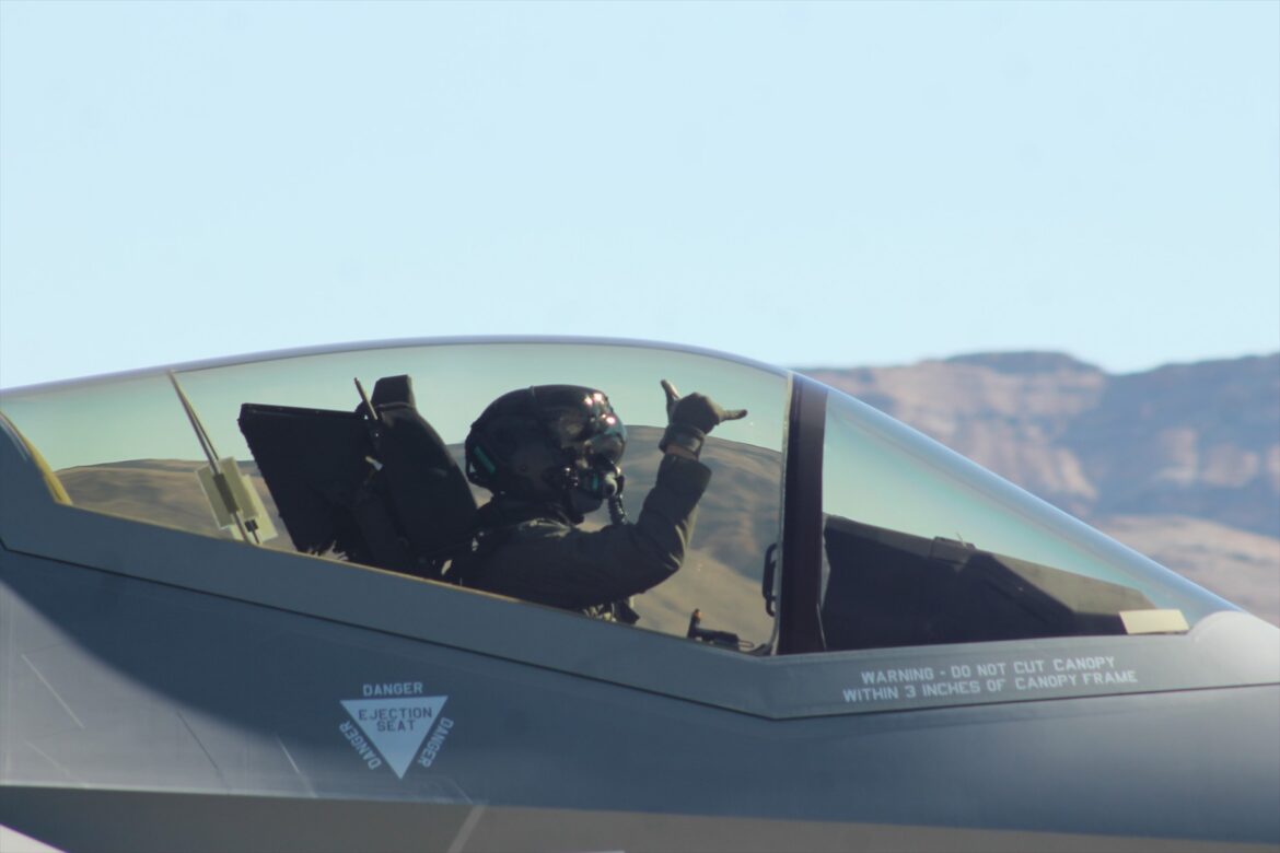Pilot Andrew Olsen v přilbě za průhledným překrytem kokpitu F-35 zvedá pravou ruku