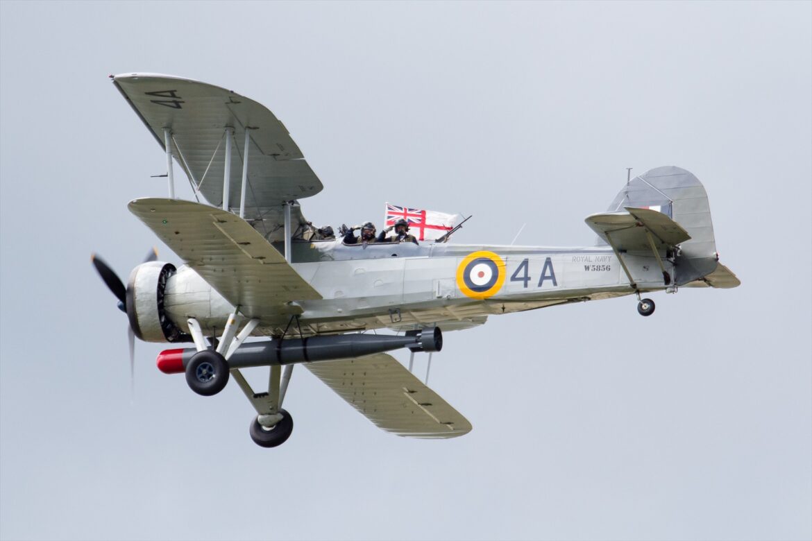 Fairey Swordfish W5856 s tříčlennou posádkou a torpédovým závěsem za letu.