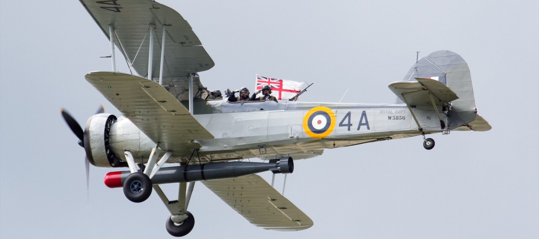 Fairey Swordfish W5856 s tříčlennou posádkou a torpédovým závěsem za letu.
