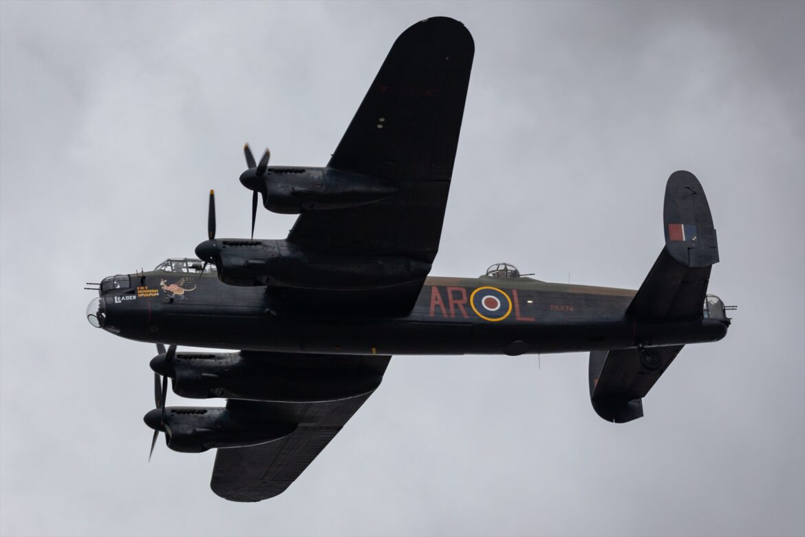 Čtyřmotorový těžký bombardér Avro Lancaster v maskovacím nátěru za letu na letecké přehlídce