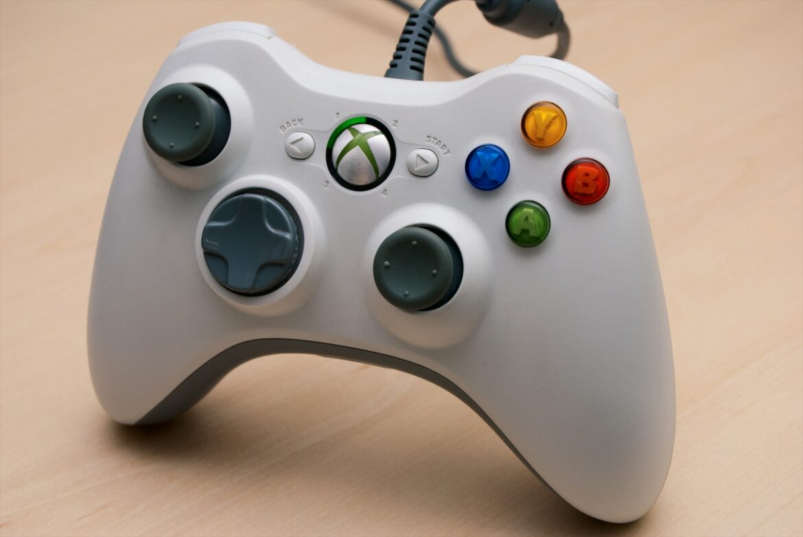 Bílý drátový herní ovladač Microsoft Xbox 360 s ovládacími páčkami a USB kabelem