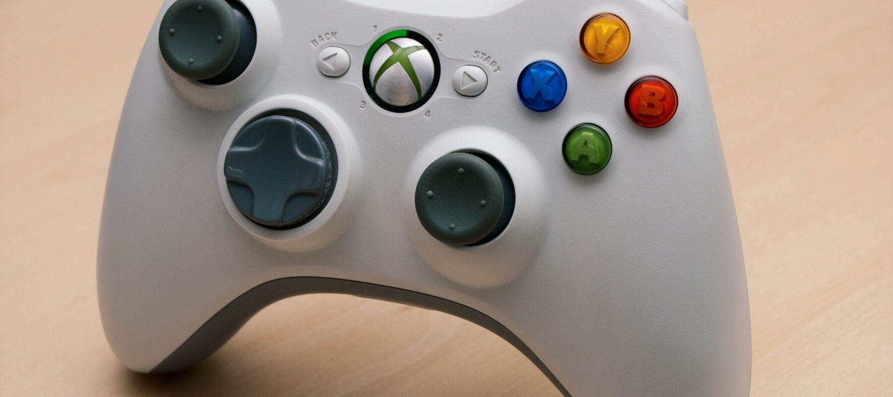 Bílý drátový herní ovladač Microsoft Xbox 360 s ovládacími páčkami a USB kabelem