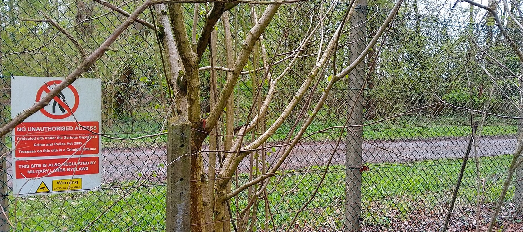 Výstražná tabule zakazující vstup na plotě v zalesněném okolí Porton Down.