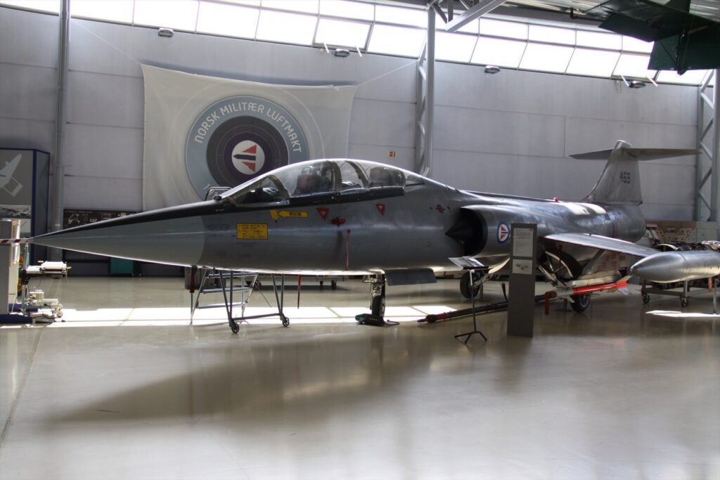 Stříbrný dvoumístný Starfighter číslo 469 vystavený v muzejním hangáru.