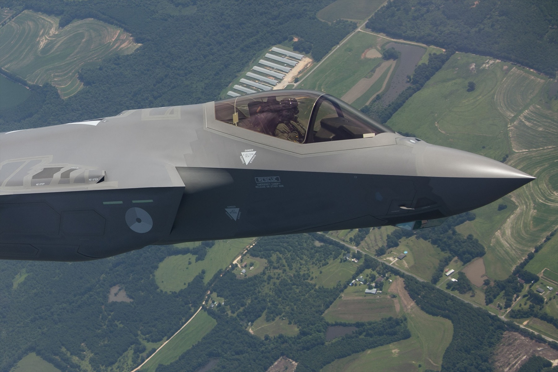 Přední část nizozemské F-35 s pilotem pod uzavřeným překrytem za letu nad krajinou