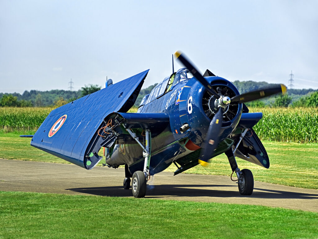 Těžký palubní torpédový letoun Grumman Avenger v modré kamufláži s otevřeným překrytem kabiny během letecké přehlídky.