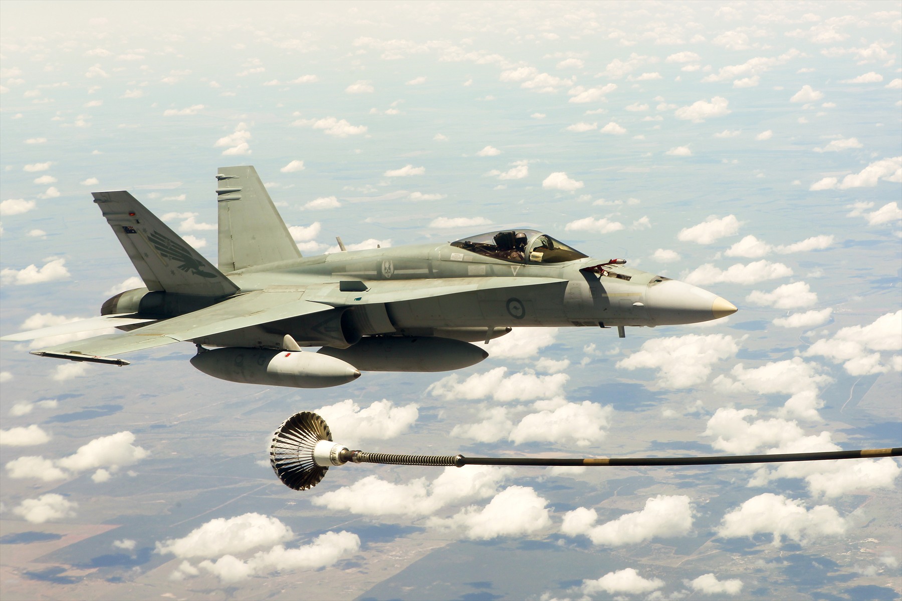 Australský F/A-18 Hornet letí poblíž koše na konci tankovací hadice.