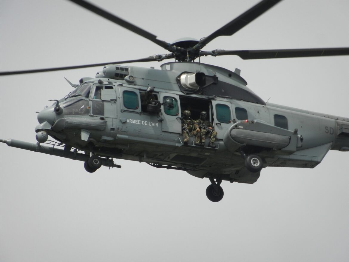 Těžký vojenský vrtulník Airbus EC725 Caracal v šedé kamufláži za letu se sondou pro doplňování paliva