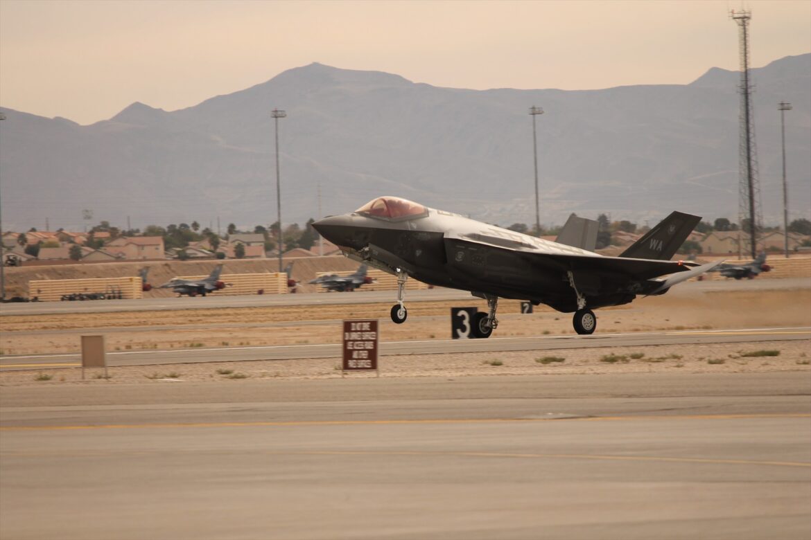 Bojový letoun F-35A Lightning II dosedající na vzletovou a přistávací dráhu se zapnutými pozičními světly a vysunutým podvozkem.