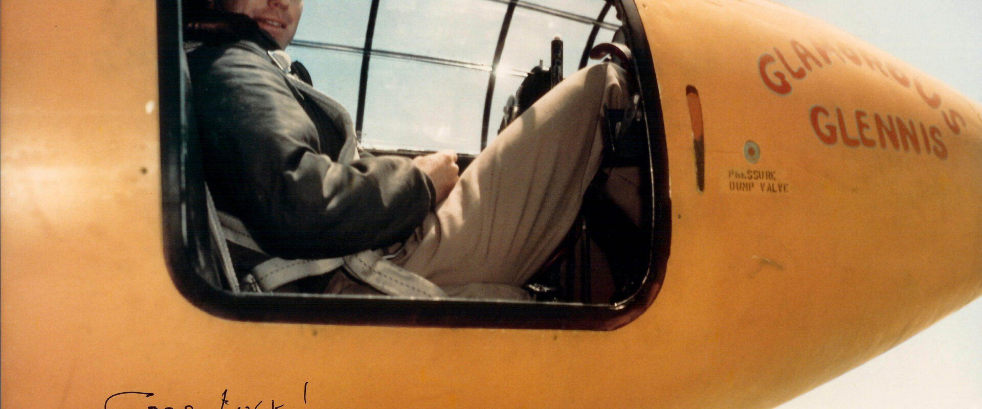 Kapitán Chuck Yeager v pilotní kombinéze stojí u oranžového raketového letounu Bell X1 Glamorous Glennis
