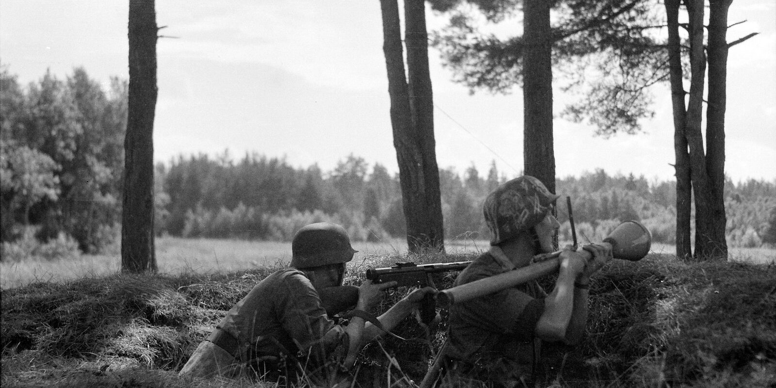 Německý voják v polní uniformě mířící z pancéřové pěsti Panzerfaust s trubicí založenou pod paží.