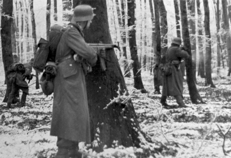 Němečtí vojáci postupující zimní krajinou s útočnými puškami StG 44 v rukou