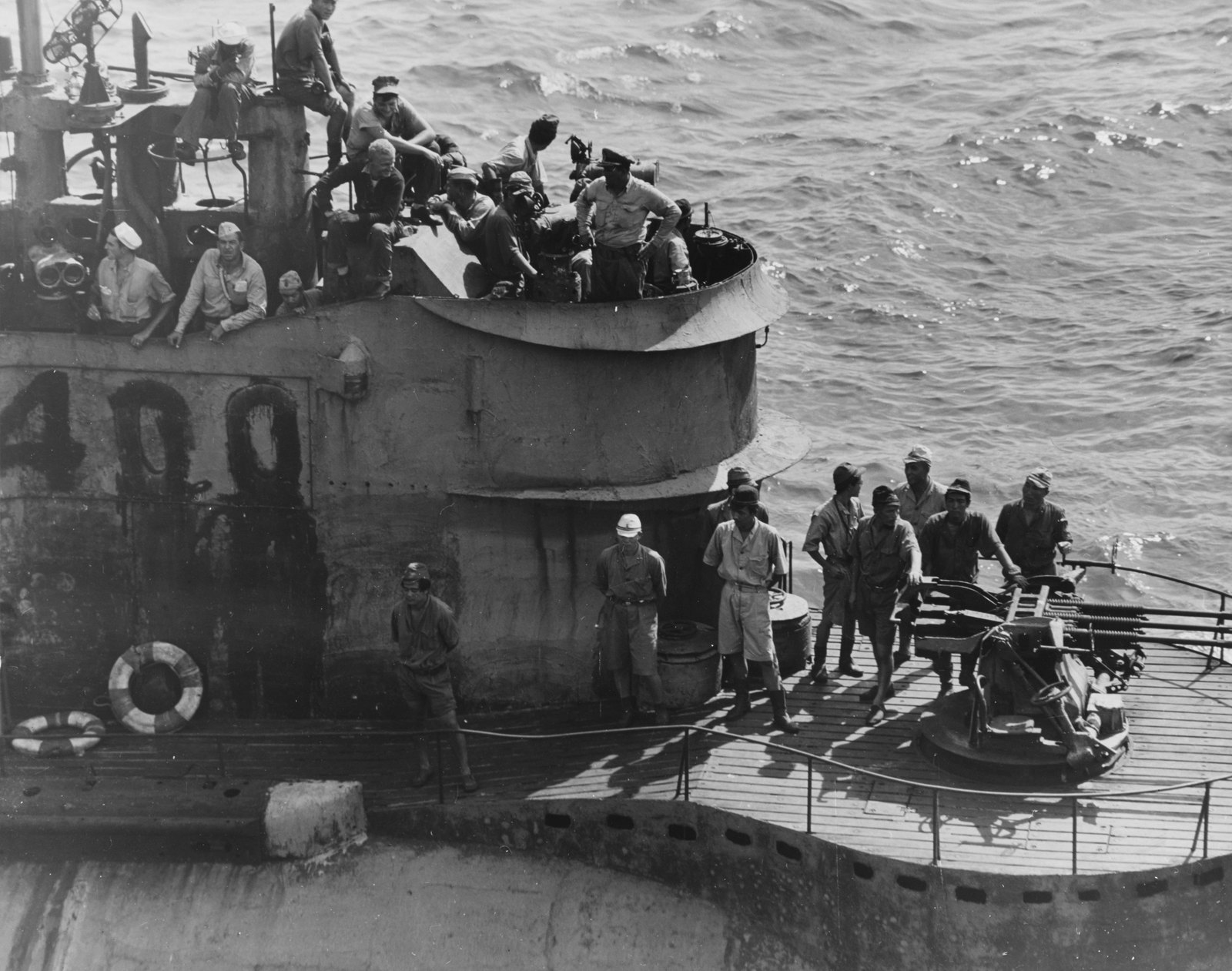 Posádka na palubě japonské ponorky I-400 u otevřeného válcového hangáru pro tři bombardéry.