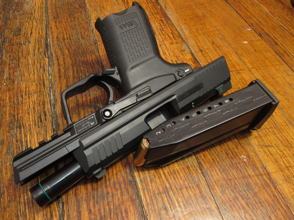 Poloautomatická pistole Heckler & Koch HK45 ráže čtyřicet pět položená na stole.