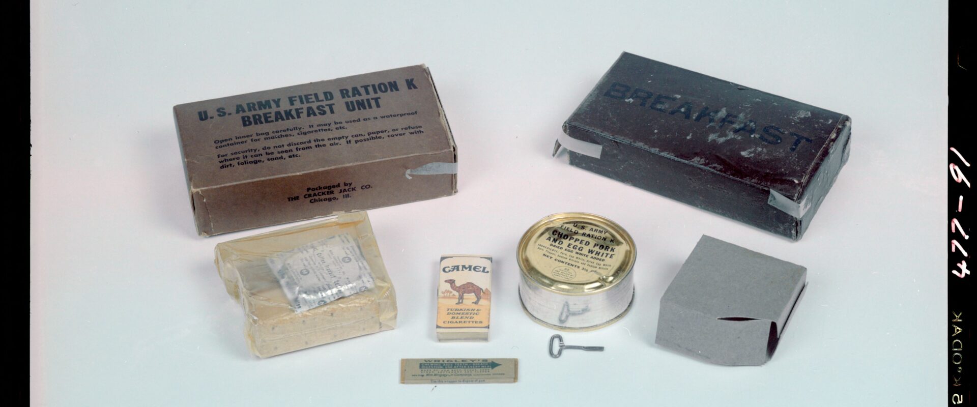 Rozložená polní dávka K-Ration se snídaňovou konzervou šunky a vajec, suchary, kávou a cigaretami