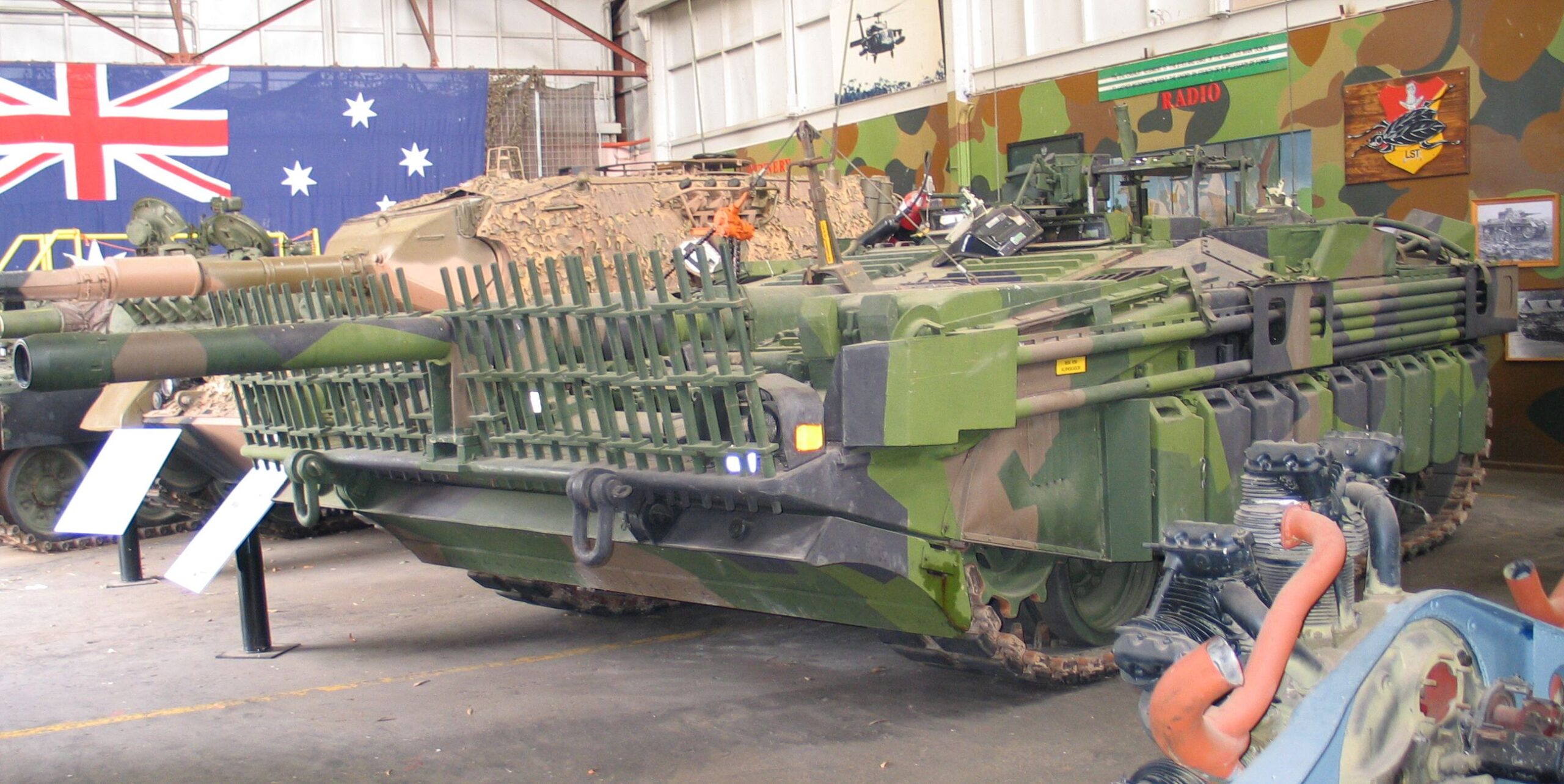 Boční a přední pohled na nízký švédský tank Stridsvagn 103C vystavený v muzeu.